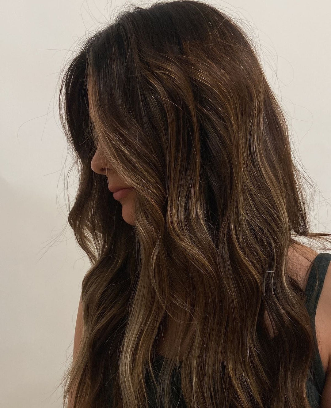 Wavy brunette hair with soft, blended highlights and natural dimension