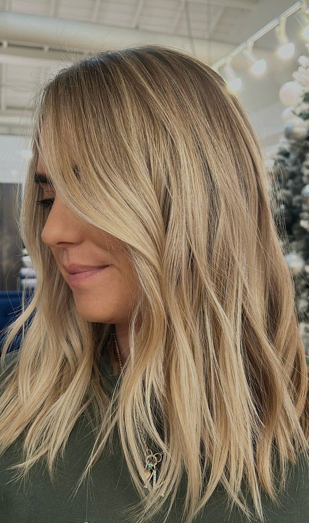 Soft lived-in blonde with layered waves and face-framing highlights in salon setting