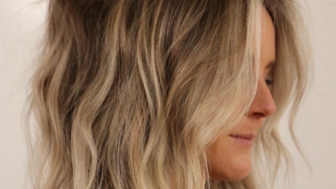 Soft lived-in blonde with natural root shadow and dimensional waves, creating a seamless, low-maintenance finish