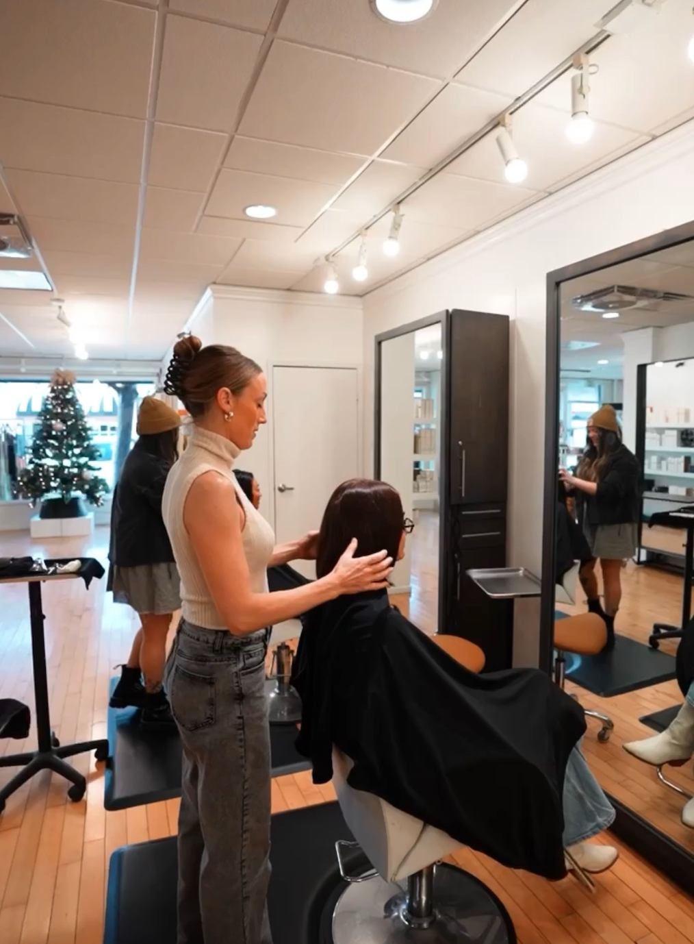 Stylist consulting with client during haircut at modern hair salon, mirror view.